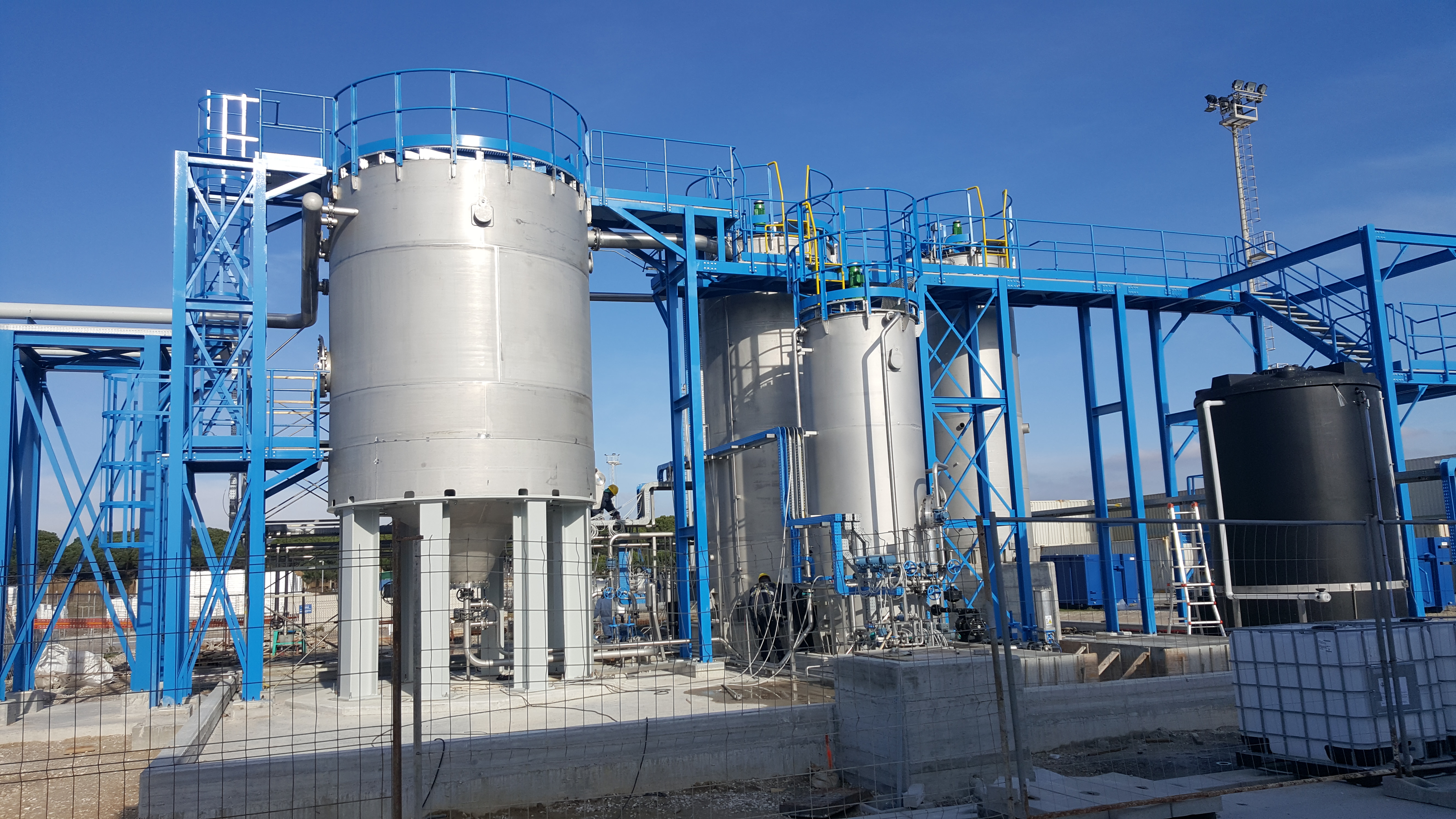 Impianto industriale con apparecchi verticali, carpenterie blu, passerelle e tubazioni